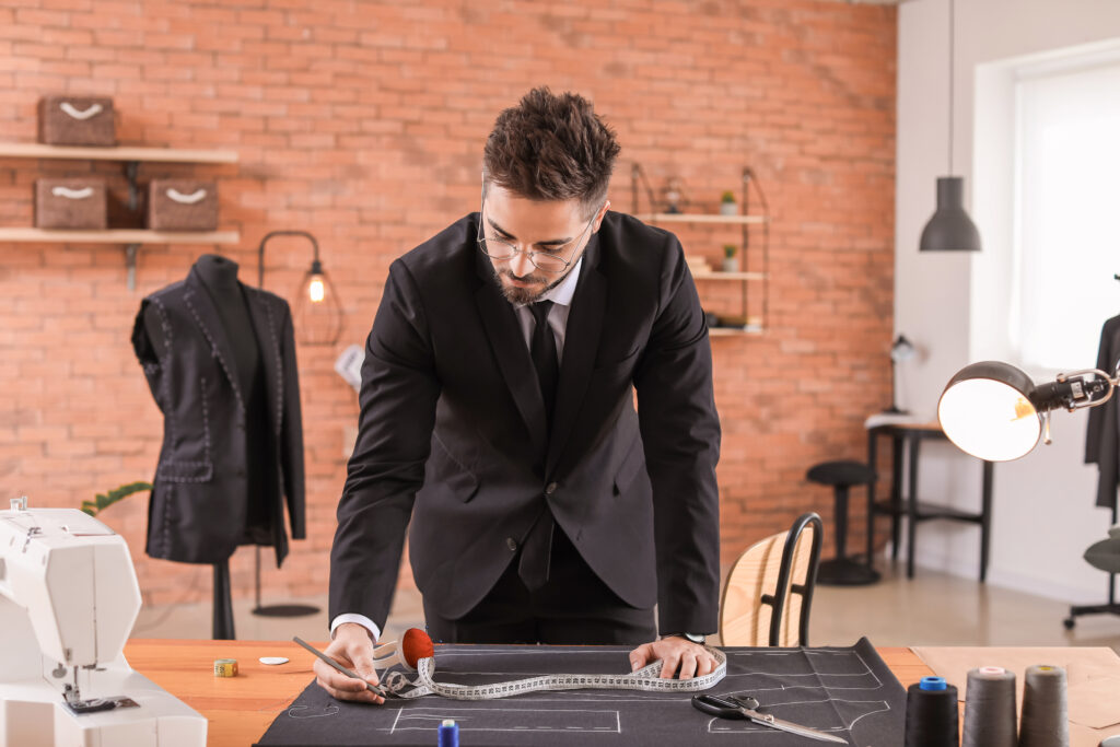 Young tailor working at table in atelier